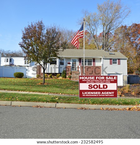 American Flag pole Real Estate Sold (another success let us help you buy sell your next home) sign suburban bungalow home autumn day residential neighborhood blue sky USA