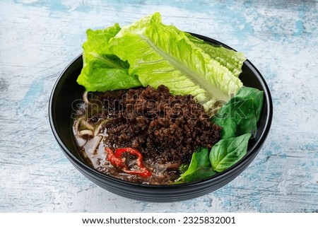 Noodle soup, minced pork, chili, lettuce and spinach. Broth with meat, egg noodles and greens.