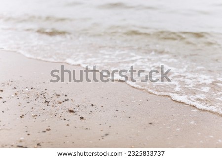 serene beach scene with golden sand, colorful beach sandals, sparkling water, and a bright daytime sky, representing relaxation, leisure, and the joys of coastal living