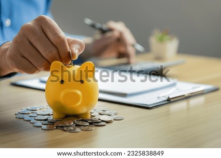 Businessman calculates savings on his desk and piggy bank and piles of coins. investment and savings family spending plan, Calculate interest rates and dividends at retirement.