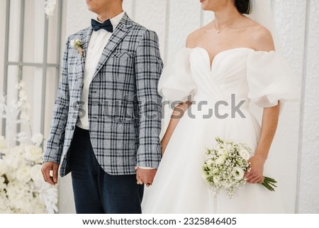 Marriage closeup. Bride and groom getting married and hold hands. Engagement. Newlyweds stands on wedding ceremony under arch decorated white flowers. Woman and man while ceremony. Bridal photo.