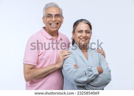 Portrait of loving senior Indian couple, standing on white background.