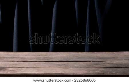Wooden Table with Black Fabric Backdrop Design: Contemporary Interior Decor for Home and Office Spaces. Empty Wooden Table on Black Fabric Background for Graphic Design and Product Presentations.