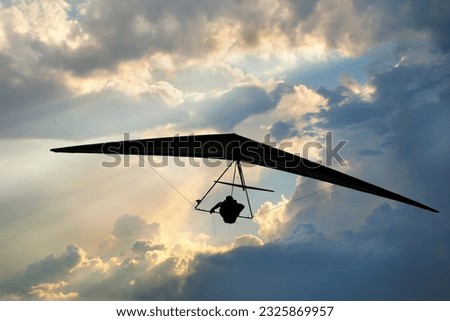 Real racing sport hang glider silhouette with dramatic sky on the background.  Royalty-Free Stock Photo #2325869957