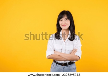 Young Businesswoman. Portrait asian woman happy smiling, posing confident, cross arms on chest, standing against yellow studio background. Young smart entrepreneur advertising products and services.
