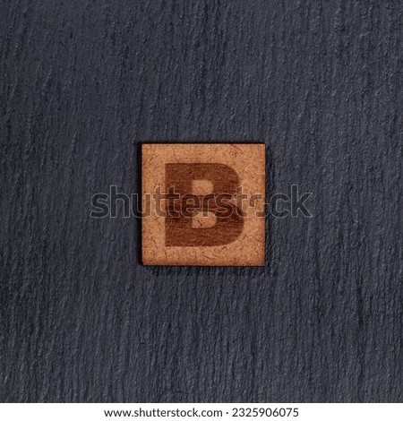 Capital Letter In Square Wooden Tiles - Letter B, On Black Stone Background.