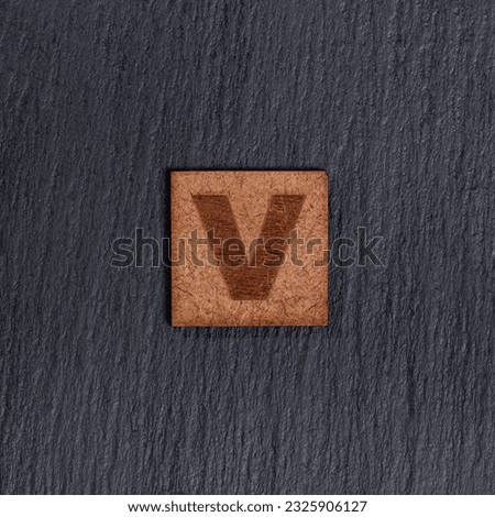 Capital Letter In Square Wooden Tiles - Letter V, On Black Stone Background.