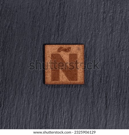 Capital Letter In Square Wooden Tiles - Letter N, On Black Stone Background.