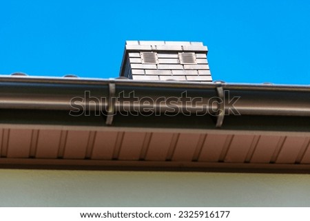 Brown brick chimney with two ventilation grilles, bottom view, focus on the chimney