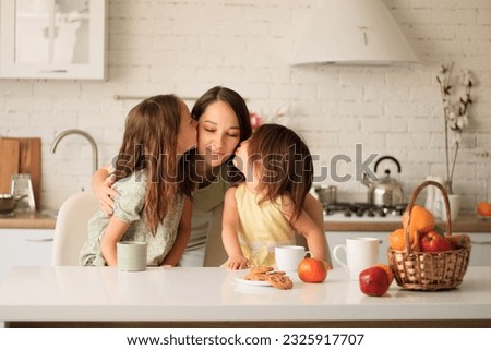 mother and daughter have breakfast at the kitchen table. Kiss mom on the cheeks