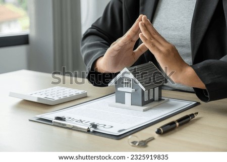 Hand a real estate agent hand prevent the home model and explain the business contract, rent, buy, mortgage, loan, or home insurance.