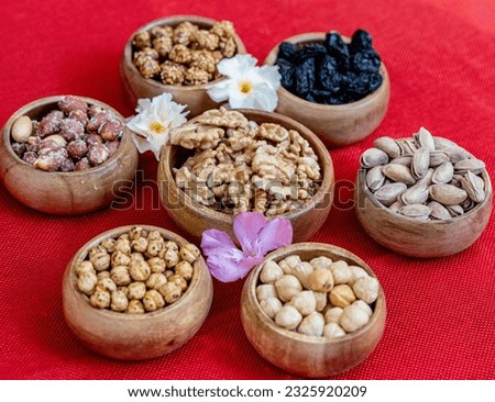 Various kinds of nuts, peanuts, chickpeas, raisins in a wooden bowl on a red background