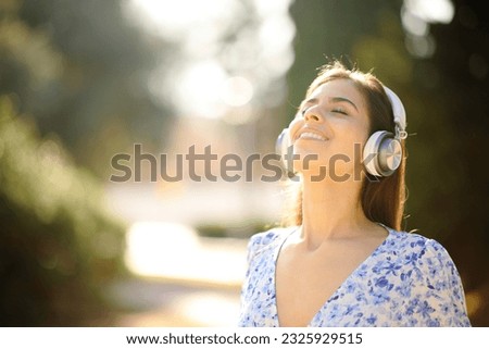 Happy woman relaxing mind breathing with headphone in a park Royalty-Free Stock Photo #2325929515