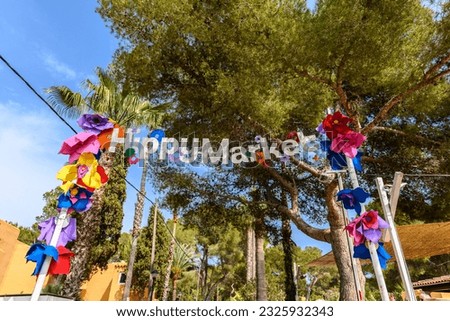 Entry sign to the Punta Arabi hippy market in Es Canar, Ibiza, Spain. The sign is decorated with colorful paper flowers. Punta Arabi is the oldest and biggest hippy market in Ibiza. Royalty-Free Stock Photo #2325932343