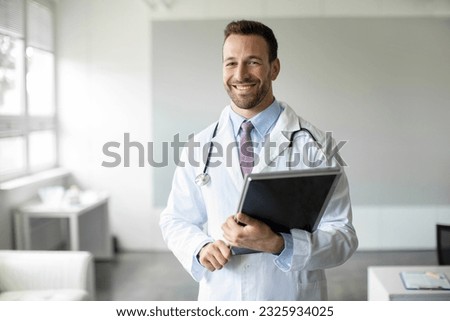 Portrait of cheerful man doctor holding clipboard smiling at camera, male physician gp working in clinic, wearing white medical uniform, copy space Royalty-Free Stock Photo #2325934025