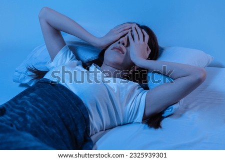 Annoyed, Stressed, asian young beautiful, pretty woman, girl suffering from insomnia, awake in bed at night, covering face with hand because of disturbed loud noise, unable sleep. Restless people. Royalty-Free Stock Photo #2325939301