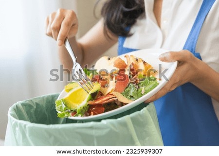 Compost from leftover food asian young housekeeper woman, female hand holding salad bowl use fork scraping waste, rotten vegetable throwing away into garbage, trash or bin. Environmentally responsible Royalty-Free Stock Photo #2325939307