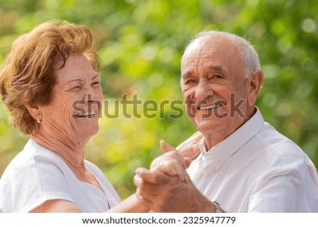 smiling senior couple dancing happily outdoors