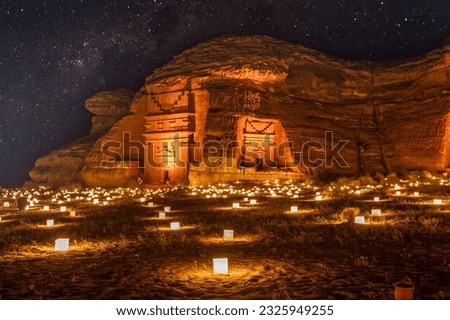 Starlight sky over the ancient nabataean tombs of Mada'in Salih Hegra city illuminated, night panorama, Al Ula, Saudi Arabia Royalty-Free Stock Photo #2325949255