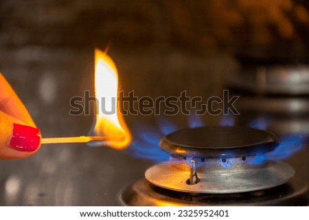 A girl sets fire to a gas burner with matches Royalty-Free Stock Photo #2325952401