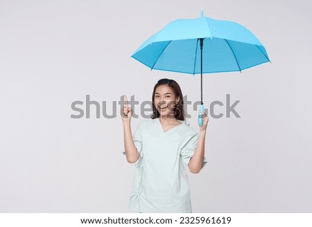 Happy smiling Asian woman standing and holding blue umbrella and pointing finger to isolated on white copy space background, life insurance and protection concept.