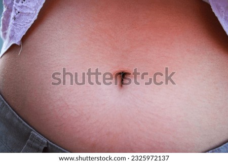 a belly button of a caucasian woman shot at sunset Royalty-Free Stock Photo #2325972137