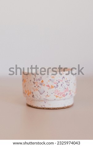 Craft candle in concrete terrazzo form at light background
