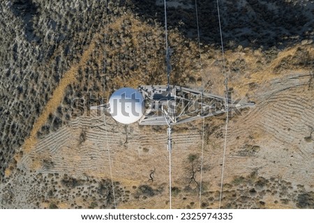 Aerial photo of a high tension column on the mountain of Granada, at the tip of the column there is a sphere, it is one on the ground there are trees and bushes