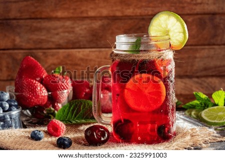 Glass of red drink with ice. blueberries, strawberries, lemon, lime and mint leaves. Close-up.