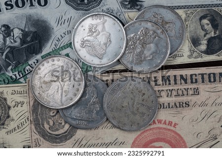 Old west US banknotes and silver certificates with silver dollar coins background