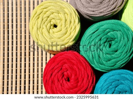 Colored skeins of thread for weaving macrame on a wooden surface. Cotton threads for knitting.