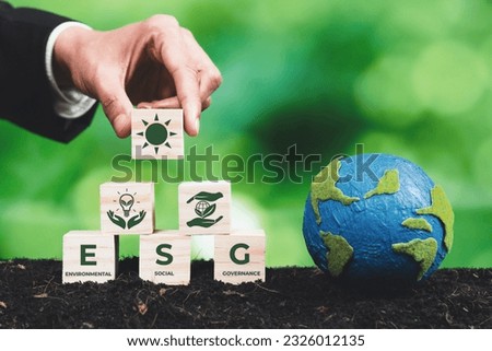 Businessman holding paper earth planet with ESG symbol wooden cube. Sustainable corporation development for environmental, social and governance idea to save the earth. Alter