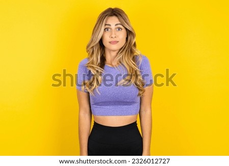 Stunned Young beautiful blonde woman wearing sportswear over yellow studio background stares reacts on shocking news. Astonished woman holds breath
