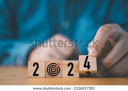 Businessman flipping of 2023 to 2024 on wooden block cube for preparation new year change and start new business target strategy concept.