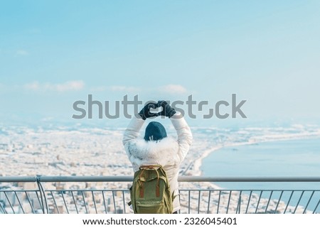 Woman tourist Visiting in Hakodate, Traveler in Sweater sightseeing view from Hakodate mountain with Snow in winter. landmark and popular for attractions in Hokkaido, Japan.Travel and Vacation concept Royalty-Free Stock Photo #2326045401