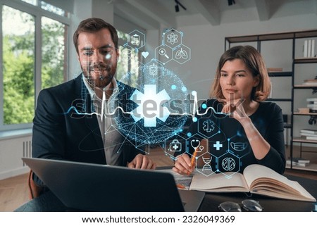 Thoughtful businesspeople typing on laptop at office workplace. Concept of team work, business education, internet surfing, brainstorm, project information technology. Medical healthcare hologram