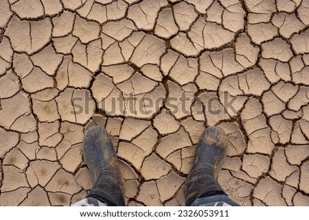 Walking in rubber boots on dry and sun-cracked silt
