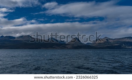 The picturesque Martial mountain range, the Andes, against a background of blue sky and clouds. View from the Beagle Canal. Argentina. Tierra del Fuego Archipelago. 