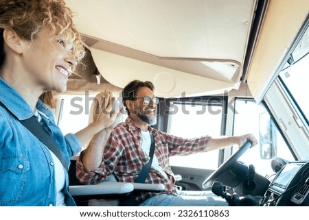 Happy couple drive and enjoy travel with camper van vehicle. Concept of renting motorhome for alternative vaction . Tourist in high five gesture inside recreational vehicle. Vanlife. Changing life Royalty-Free Stock Photo #2326110863