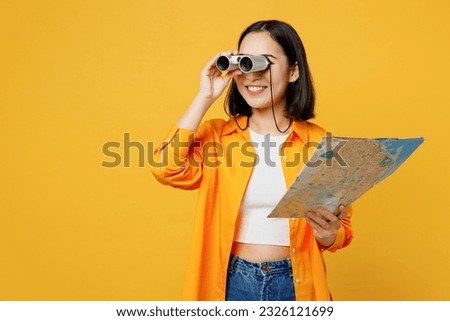 Young happy woman wear summer casual clothes hold in hand map use binoculars isolated on plain yellow background. Tourist travel abroad in free spare time rest getaway Air flight trip journey concept Royalty-Free Stock Photo #2326121699