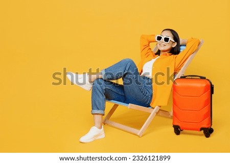 Young calm woman wear summer clothes sit in deckchair hold hands behind neck isolated on plain yellow background. Tourist travel abroad in free spare time rest getaway. Air flight trip journey concept Royalty-Free Stock Photo #2326121899