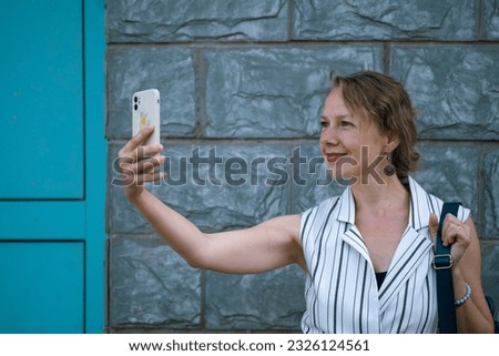 A young blonde woman takes a selfie on a city street. High quality photo