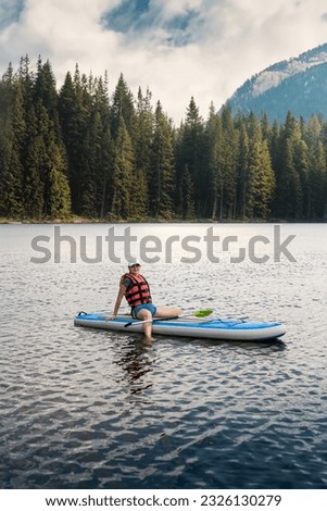 Beautiful sporty girl walks on sup paddle board at mountain lake, summer time. Just rest at nature