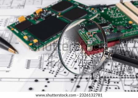 Electronic modules, magnifying glass and pen on background of  schematic circuit diagram. Concept for development and design of electronic devices.