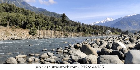 Stone pile on rock by the torrent. Water flowing through himalayan mountains. Snow water running in green jungle.