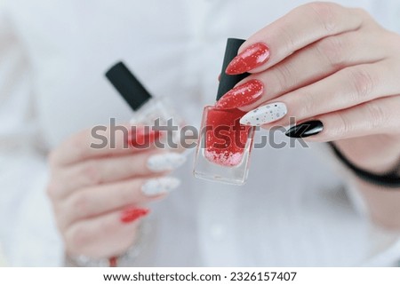 Female hands with long nails and bright red and white manicure