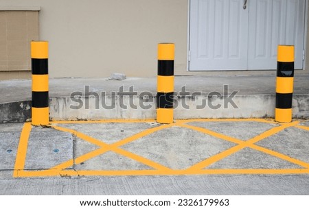 Small painted yellow and black color poles at house's front and rectangle area warning no park the car.