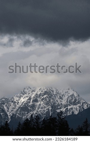 Cloud-Kissed Peaks: Serene Snowy Mountain Landscape
Nature's tranquil masterpiece unfolds as majestic snowy peaks are gently caressed by the ethereal touch of wandering clouds. Serenity at its finest.
