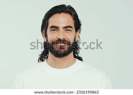 Portrait of a confident young man looking at the camera in a studio, proudly wearing a beard and long hair. Man with a beautiful appearance embracing his personal grooming and self-care. Royalty-Free Stock Photo #2326190863