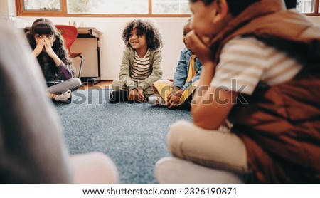 Group of children sitting in a circle in a classroom. Boys and girls enjoy learning in school, they listen their educator during a lesson. Kids schooling together in an early child development centre.